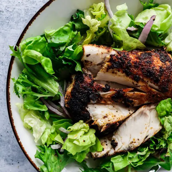 Blackened Mahi Mahi on a green salad with red onions.